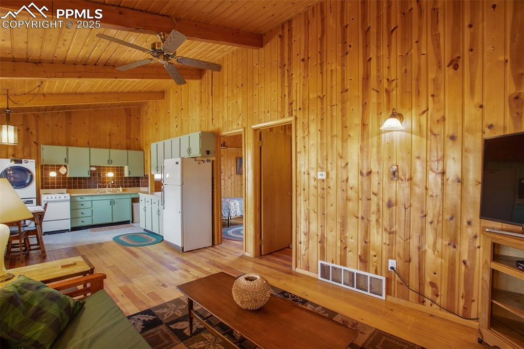 Image 7 of 38: Living room featuring wooden walls, visible vents, washer / dryer, and wood