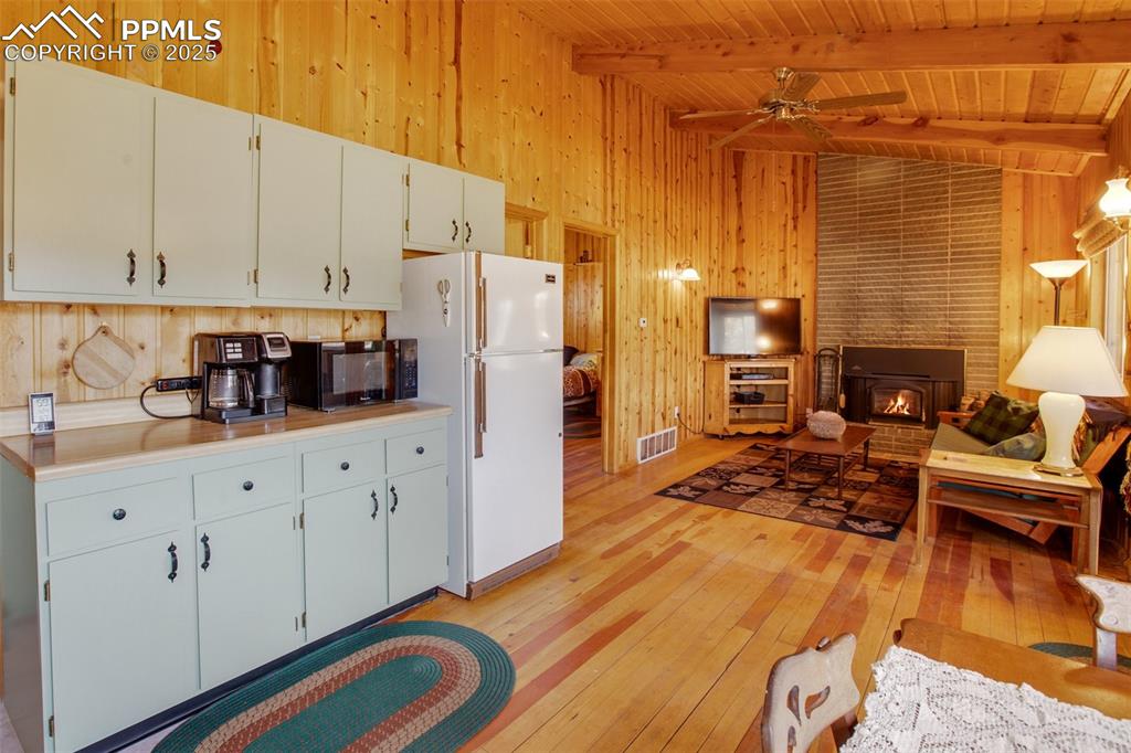 Image 8 of 38: Kitchen featuring wooden ceiling, freestanding refrigerator, wooden walls, 