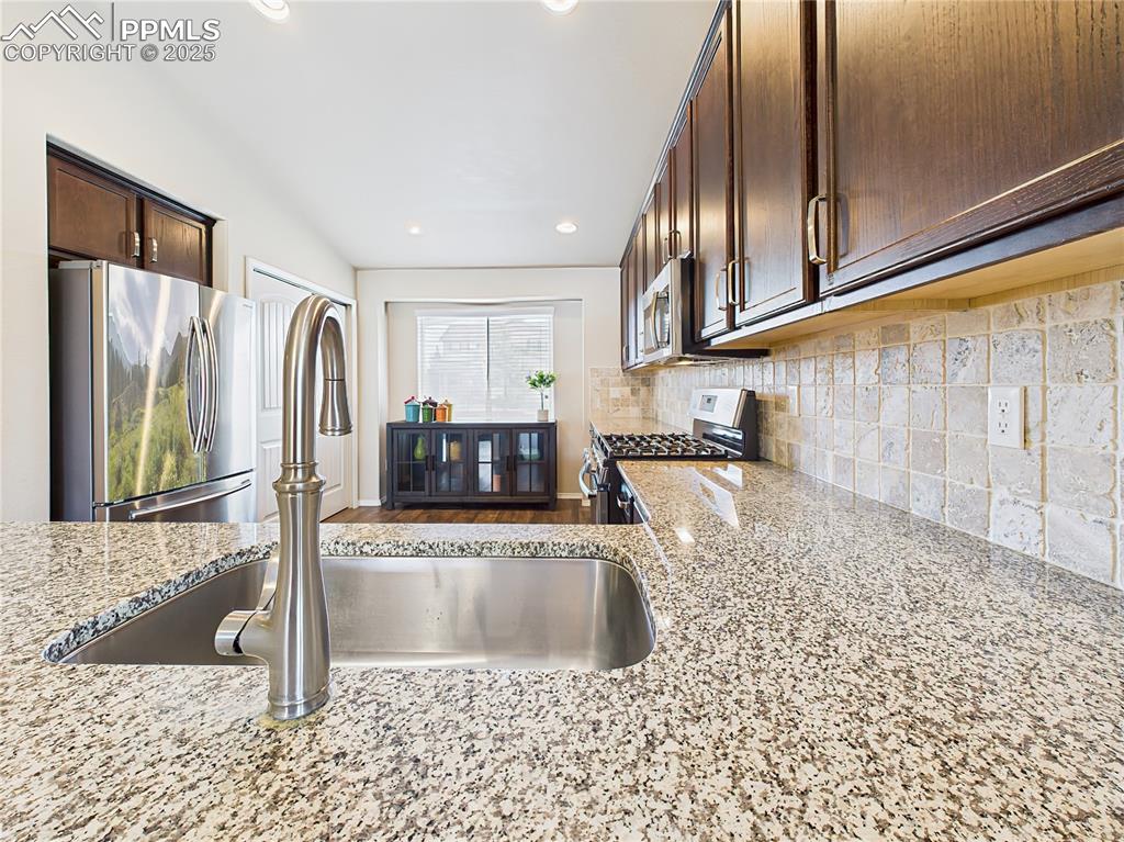 Image 12 of 50: Granite peninsula with under mount sink and bar seating provides a central 