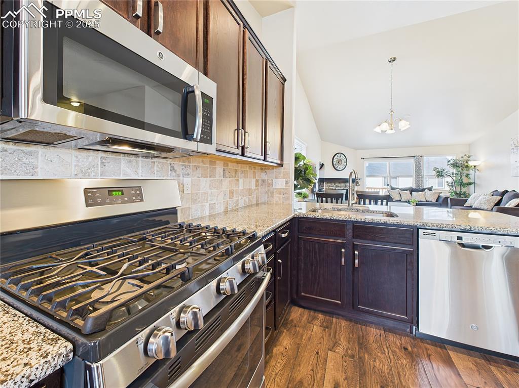 Image 13 of 50: Sleek stainless steel gas range and microwave framed by tile backsplash and