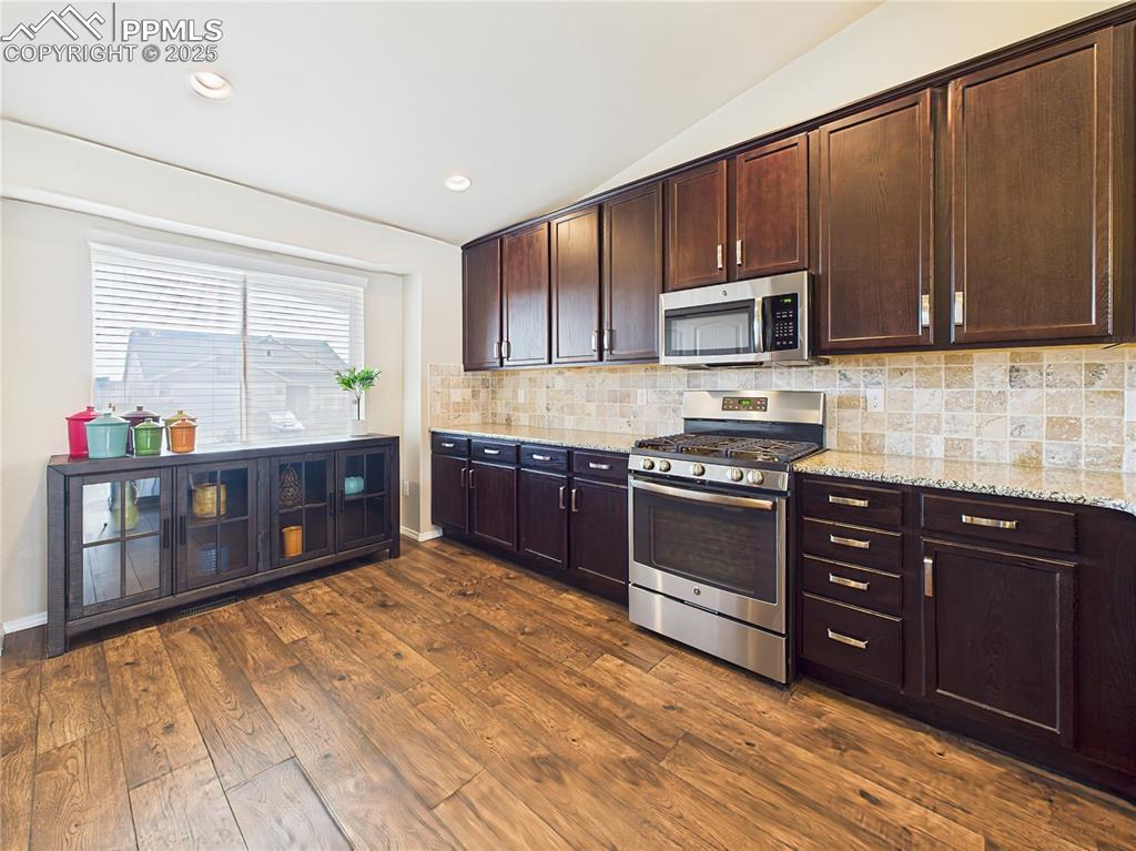 Image 14 of 50: Expansive counter space, modern backsplash, and rich cabinetry offer both s