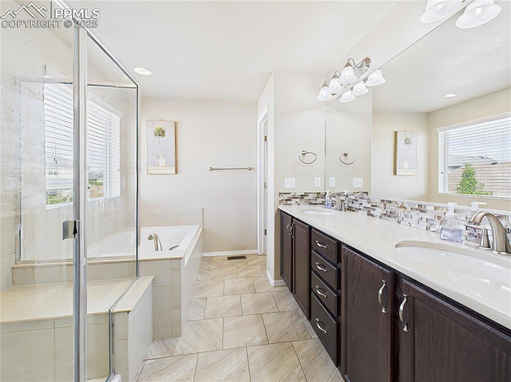 Image 20 of 50: Bright ensuite with dual vanities, framed mirrors, and stylish backsplash.