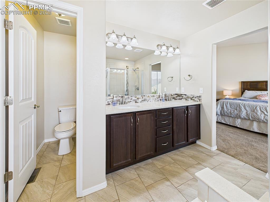 Image 22 of 50: Private water closet and extended double-sink vanity for added convenience.