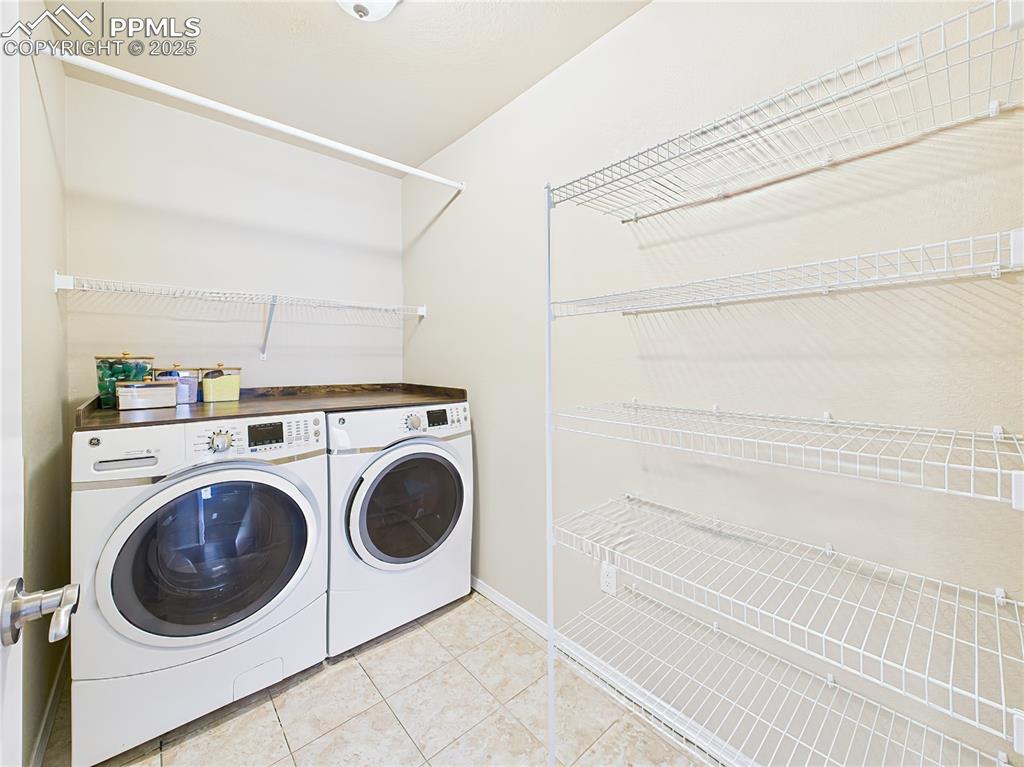 Image 26 of 50: Main-level laundry with washer/dryer, built-in shelving, and a convenient h