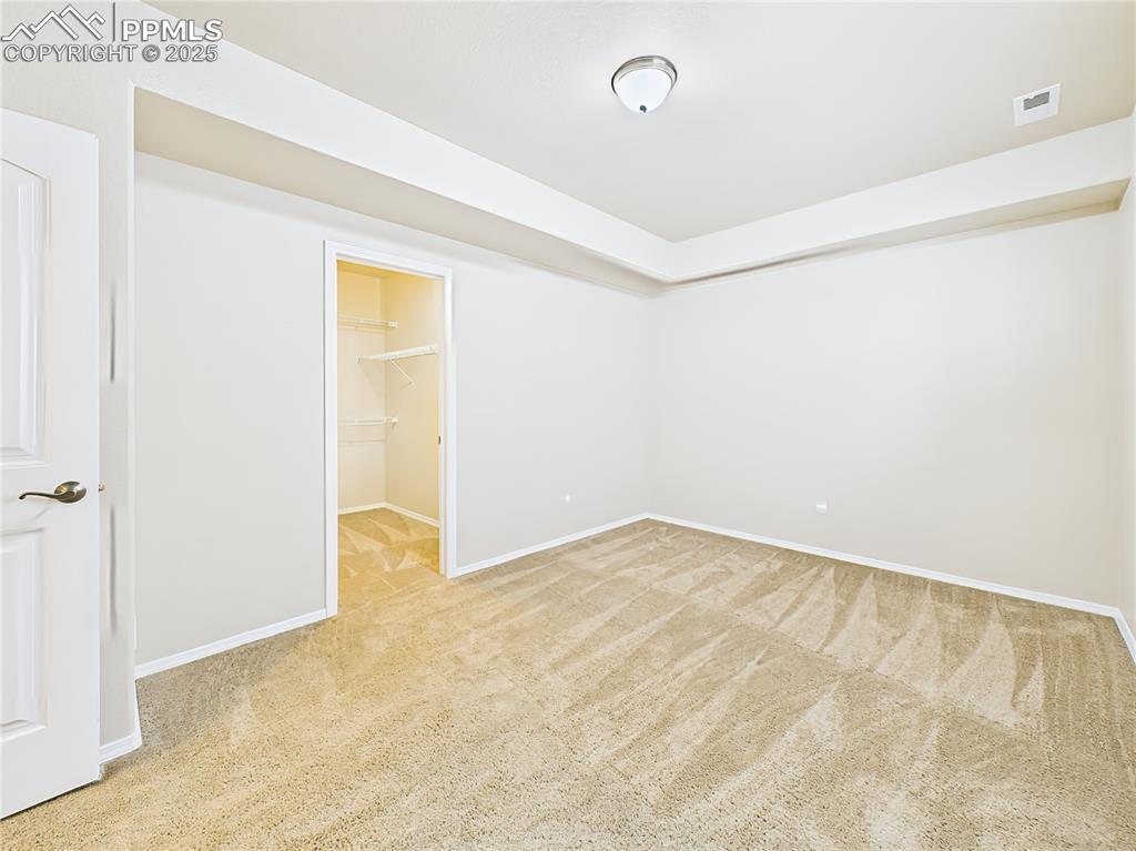 Image 34 of 50: Large lower-level bedroom with neutral tones, fresh carpet, and walk-in clo