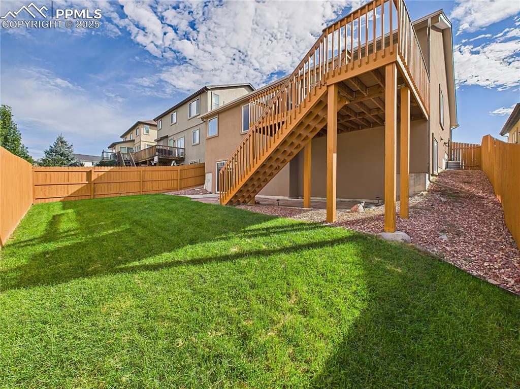 Image 44 of 50: Fully fenced backyard with lush green lawn and walk-out access from the bas