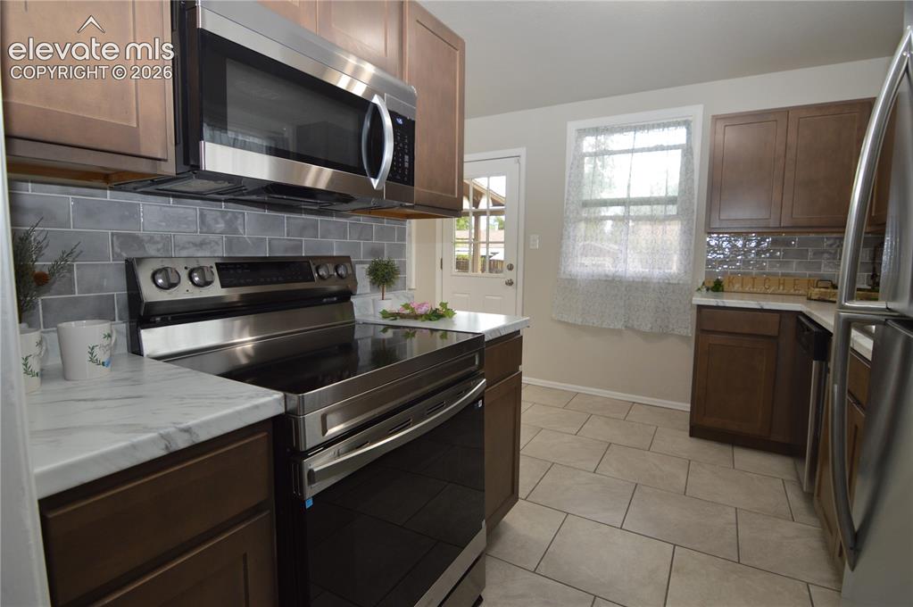 Image 5 of 23: A brand new kitchen complete with new tile floors and custom tile backsplas