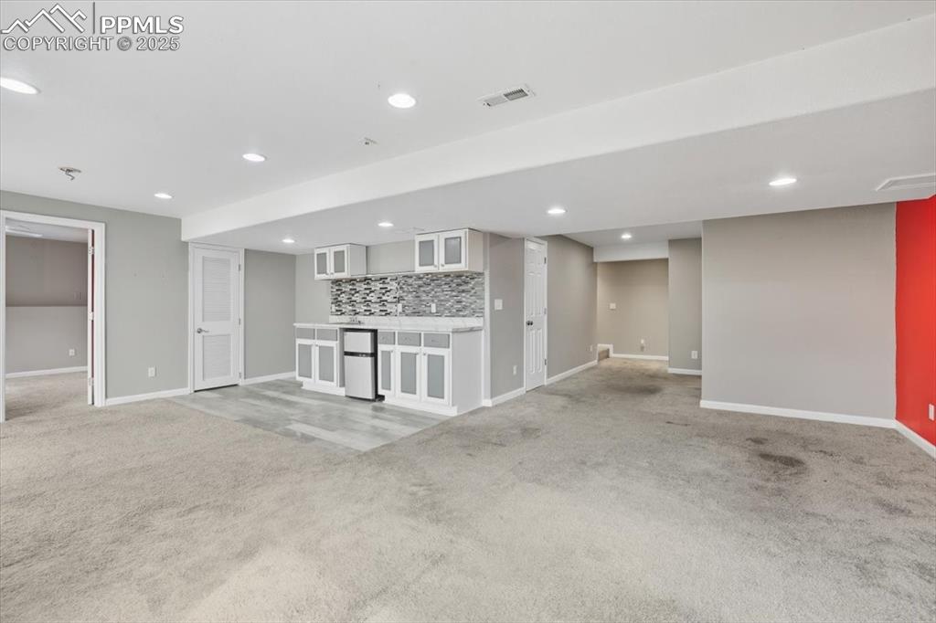 Image 26 of 44: Lower level family room with bar.