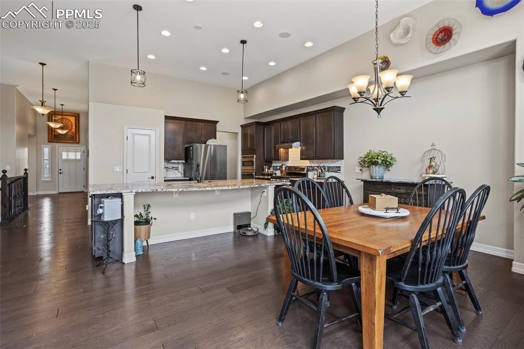 Image 10 of 47: Dining room featuring a notable chandelier, baseboards, dark wood-type floo