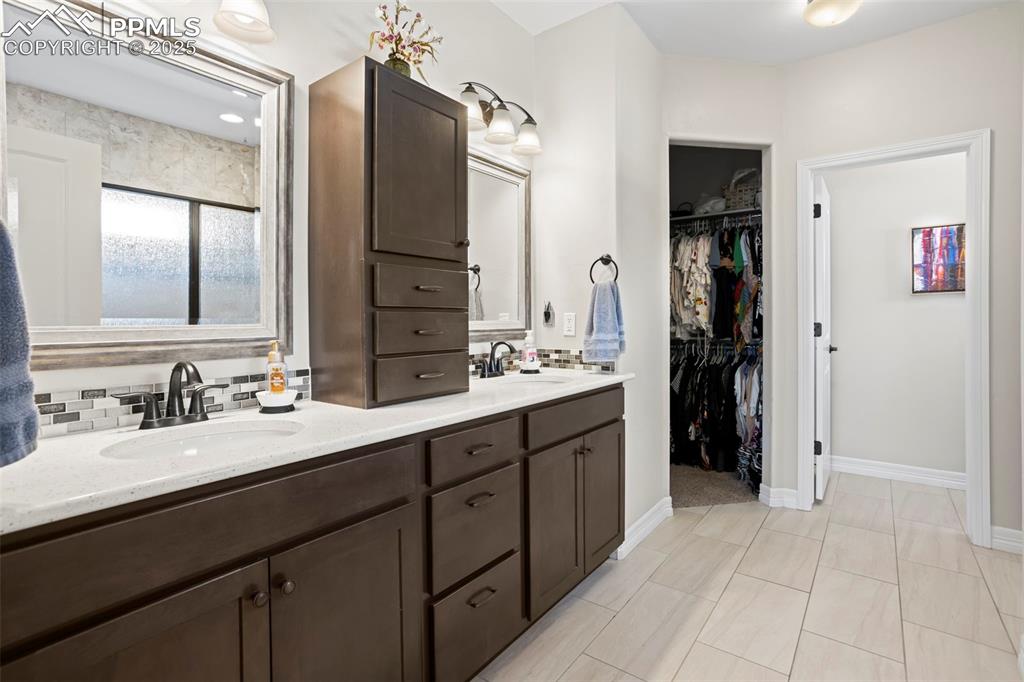 Image 15 of 47: Full bathroom with a spacious closet, backsplash, double vanity, and a sink