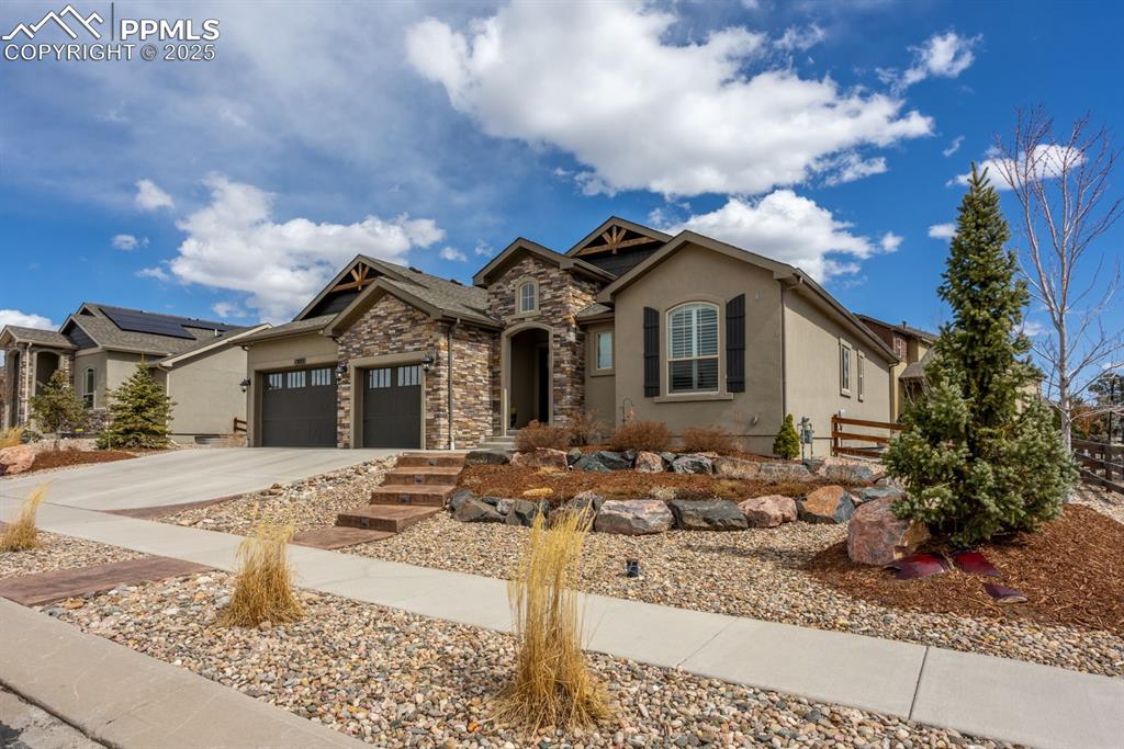 Image 2 of 47: View of front of property featuring fence, stucco siding, a garage, stone s