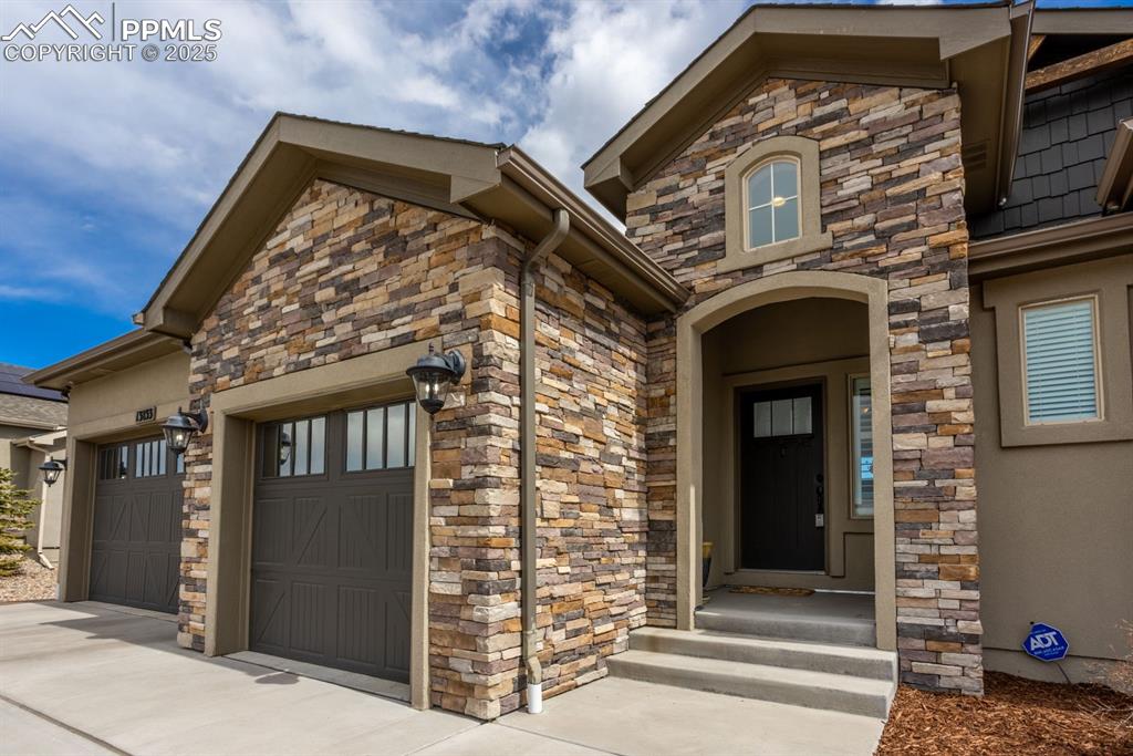 Image 3 of 47: View of exterior entry featuring stucco siding, stone siding, driveway, and