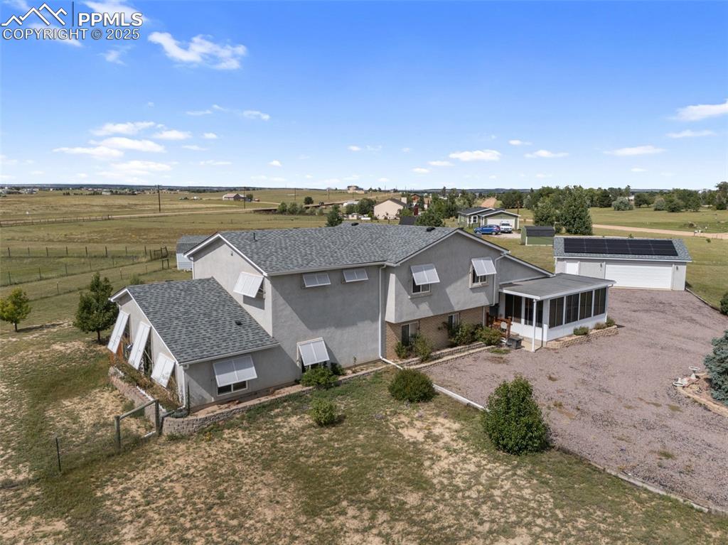Image 2 of 38: Front aerial showcasing home, garage, and outbuildings