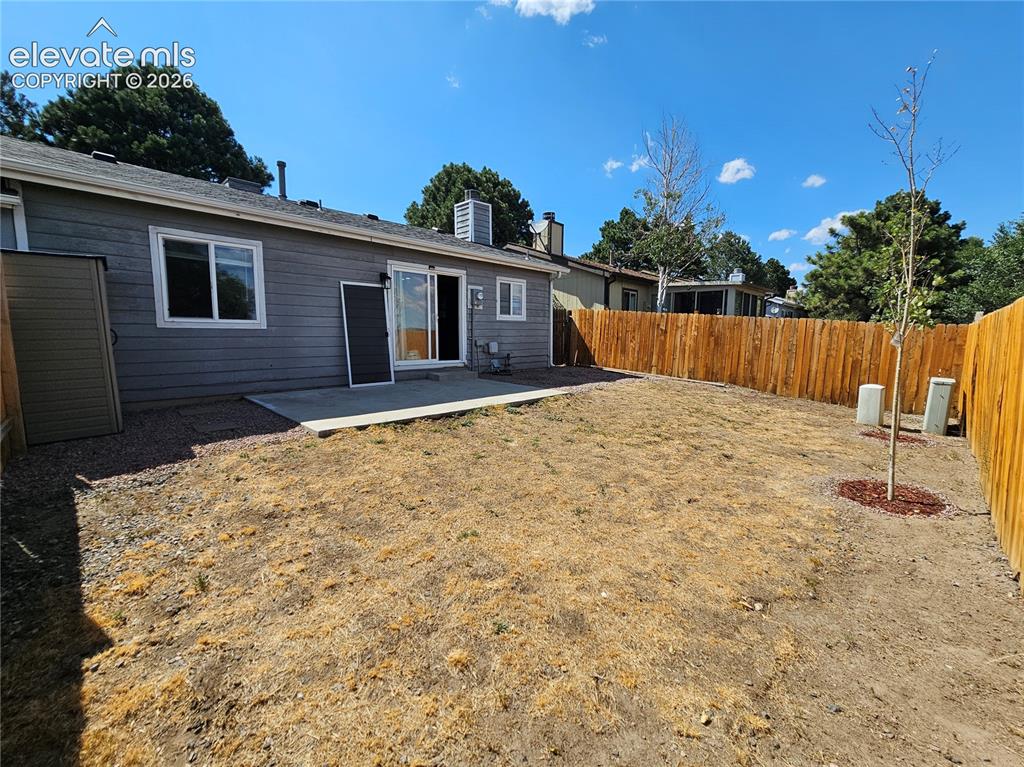 Image 14 of 15: Spacious backyard featuring a newly installed privacy fence, concrete patio