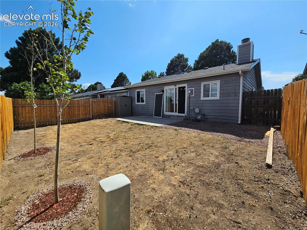 Image 15 of 15: Expansive backyard featuring a privacy fence, two young deciduous trees, an