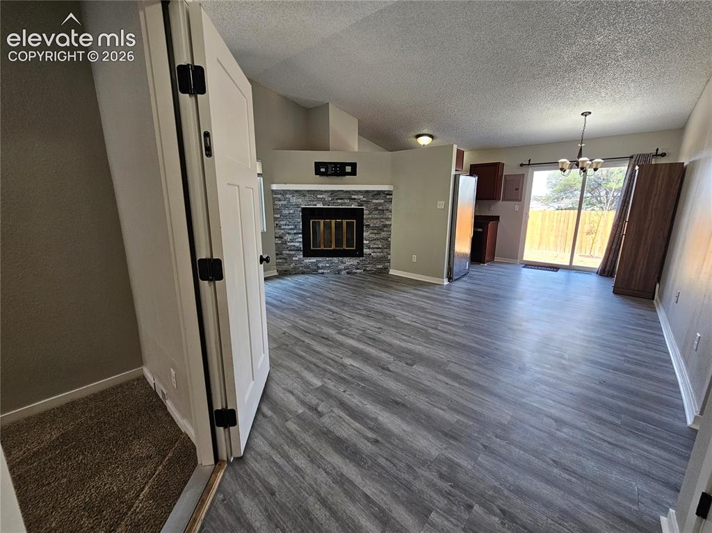 Image 2 of 15: Spacious living area featuring wood-finish flooring, a stacked stone firepl
