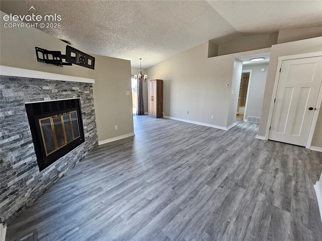 Image 5 of 15: Spacious living area featuring light wood-finish flooring, a stone-clad fir