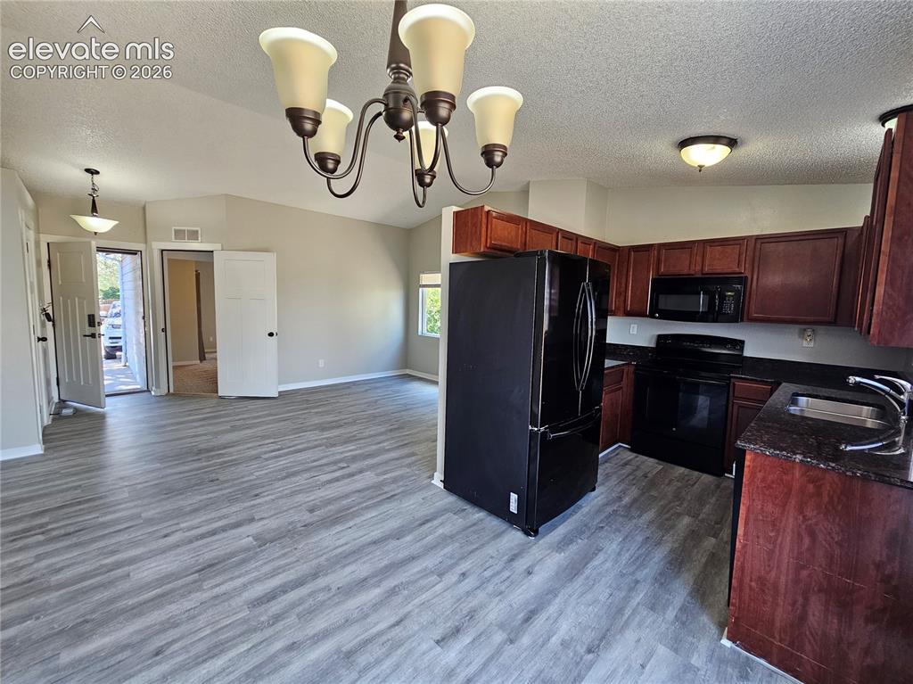 Image 6 of 15: Open-concept living space with vaulted ceilings, wood-finish flooring, and 