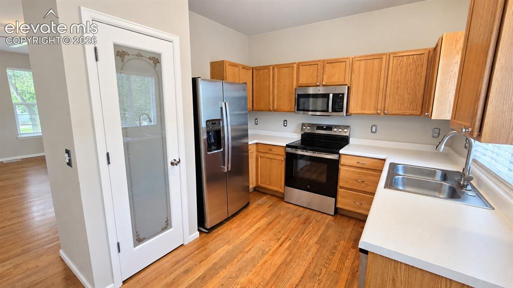 Image 11 of 27: Kitchen featuring wood-finish flooring, stainless steel appliances, light-t