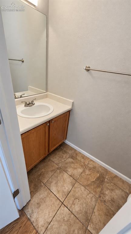 Image 12 of 27: Vanity with wood-finish cabinetry, white countertop, and an integrated sink