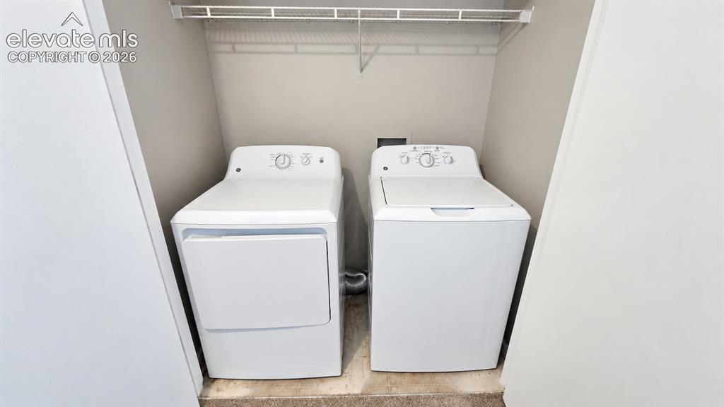 Image 13 of 27: Dedicated laundry area featuring a washer and dryer, wire shelving, and neu