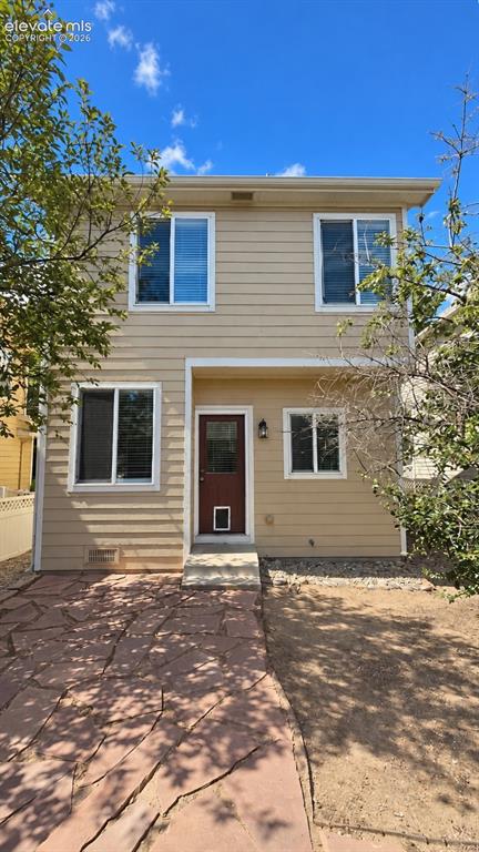 Image 21 of 27: Two-story exterior with horizontal siding, multiple windows, a red entry do