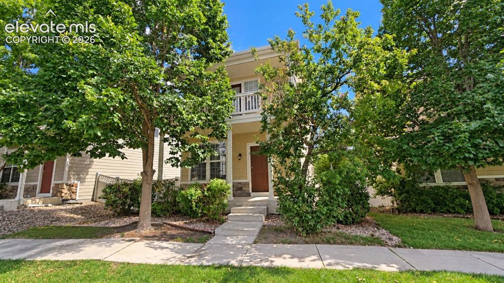 Image 22 of 27: Two-story residence featuring a balcony with white railing, stone accents o