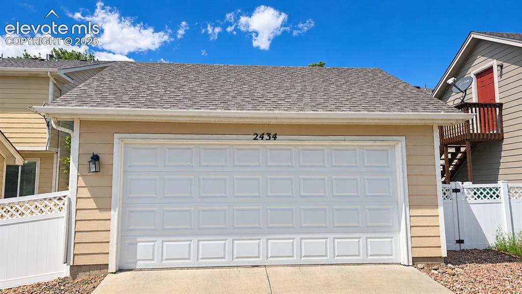 Image 24 of 27: Attached two-car garage with paneling, asphalt shingle roof, and exterior w