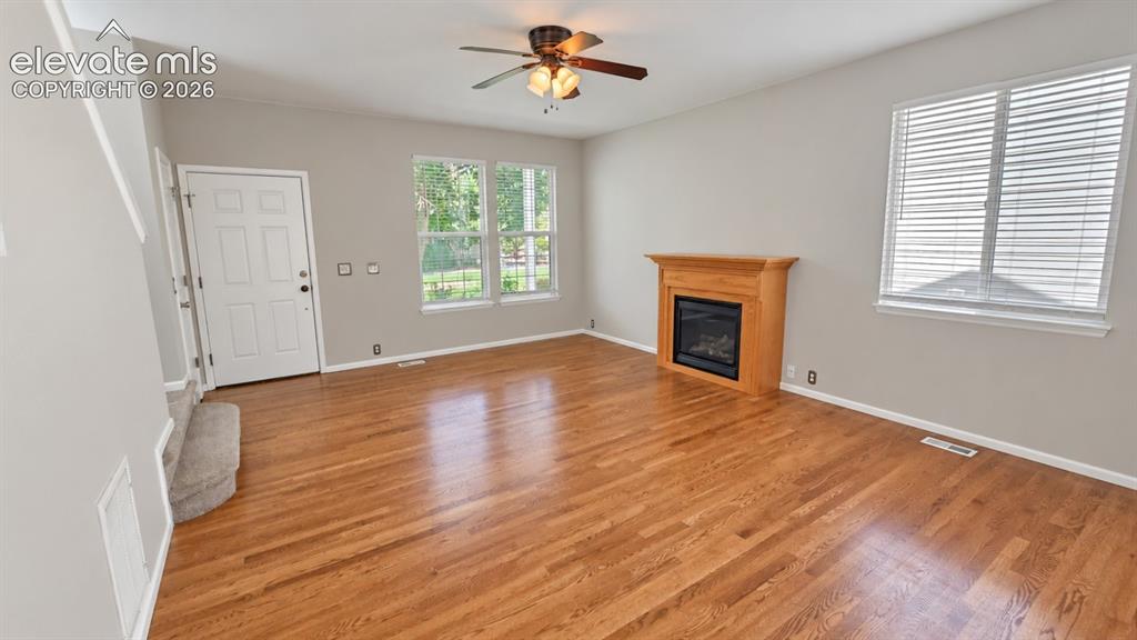 Image 4 of 27: Hardwood flooring, natural wood fireplace with black insert, multiple windo