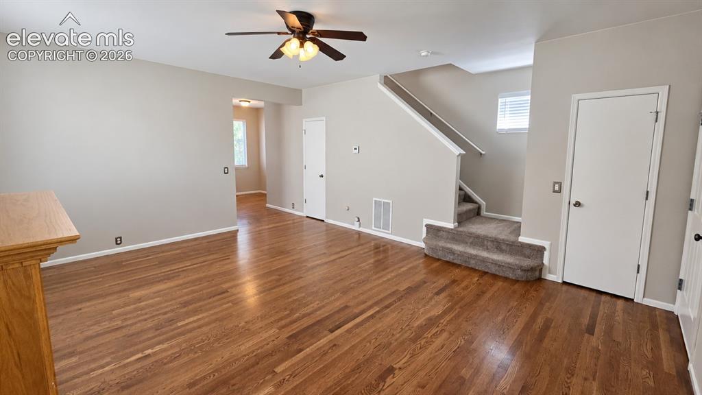 Image 6 of 27: Hardwood flooring, painted walls, ceiling fan, carpeted staircase, and whit