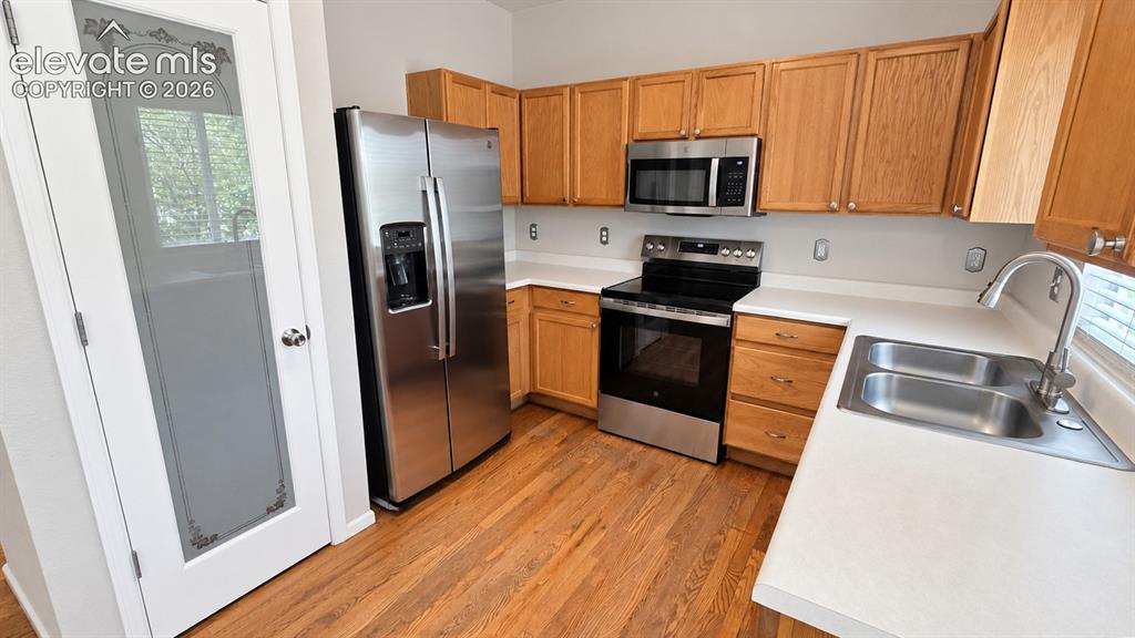 Image 9 of 27: Kitchen featuring wood-finish flooring, stainless steel appliances, light-t