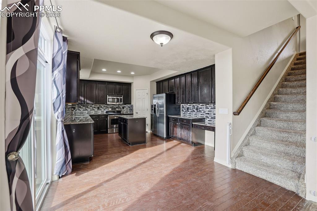 Image 15 of 39: Kitchen featuring a kitchen island, stainless steel appliances, backsplash,