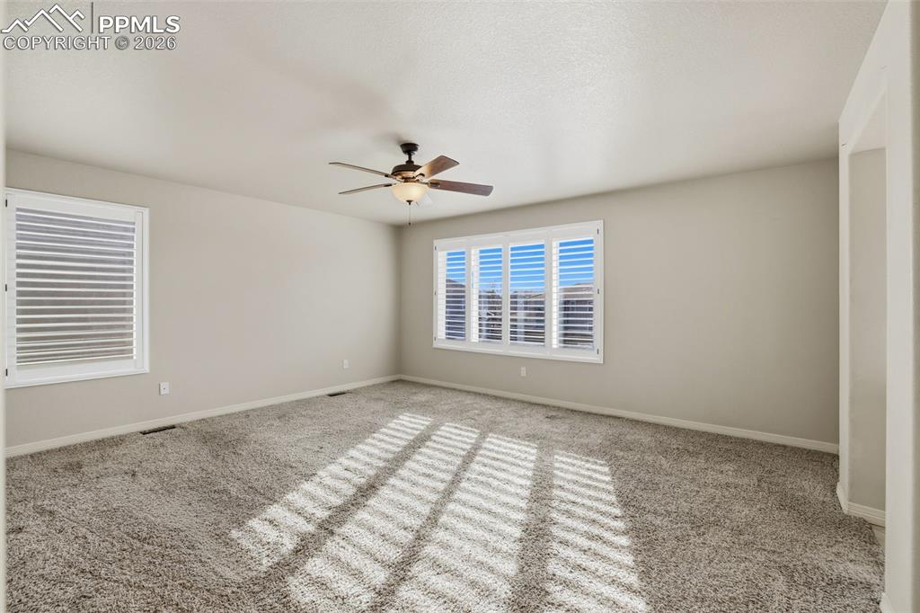 Image 27 of 39: Carpeted spare room with baseboards and ceiling fan