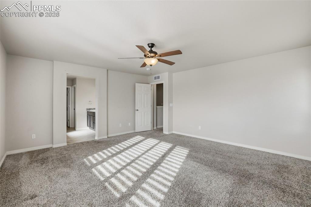 Image 29 of 39: Unfurnished bedroom with ensuite bath, light colored carpet, and ceiling fa