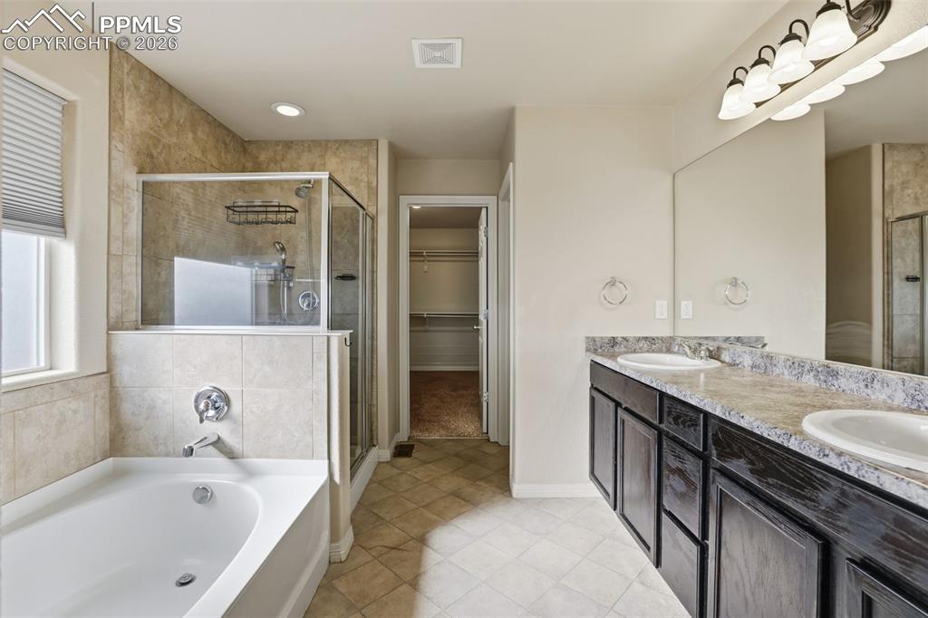 Image 30 of 39: Bathroom with a bath, a walk in closet, double vanity, a stall shower, and 