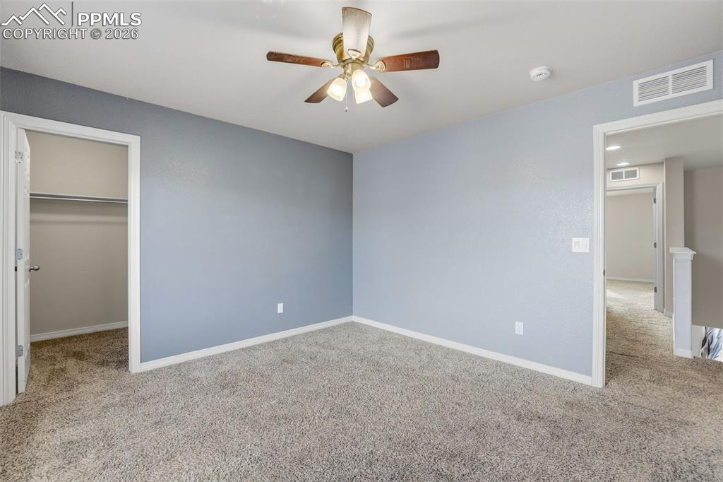 Image 34 of 39: Unfurnished bedroom featuring light carpet, a walk in closet, and ceiling f