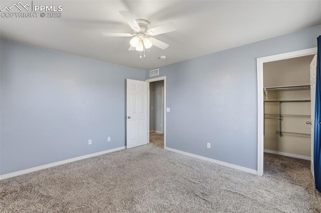 Image 36 of 39: Unfurnished bedroom with a spacious closet, carpet, and ceiling fan