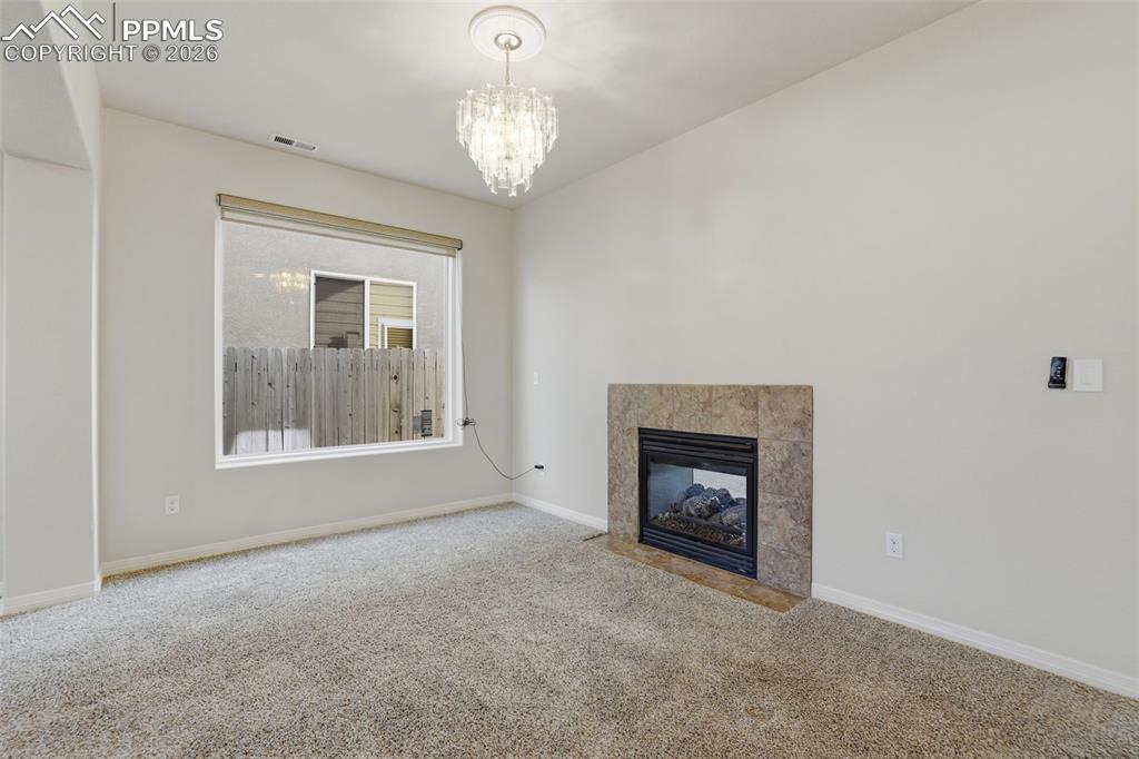 Image 9 of 39: Unfurnished living room featuring carpet flooring, a fireplace, and a chand