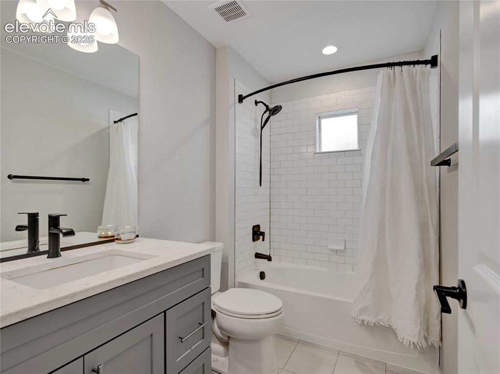 Image 11 of 17: Bathroom featuring a gray vanity with stone countertop, matte black fixture