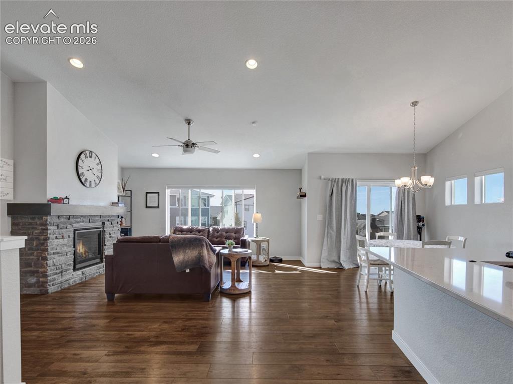 Image 2 of 17: Bright living area featuring wood-finish flooring, a stone-front fireplace,