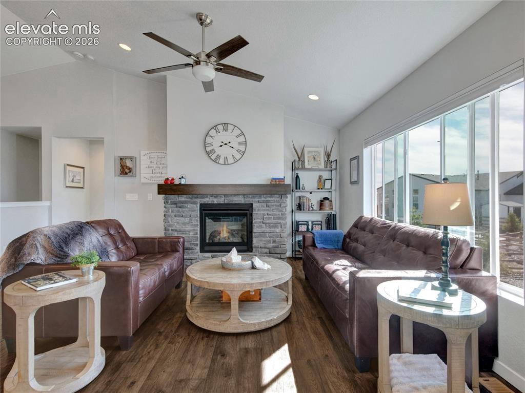 Image 3 of 17: Living area featuring vaulted ceilings, wood-finish flooring, a stone-faced