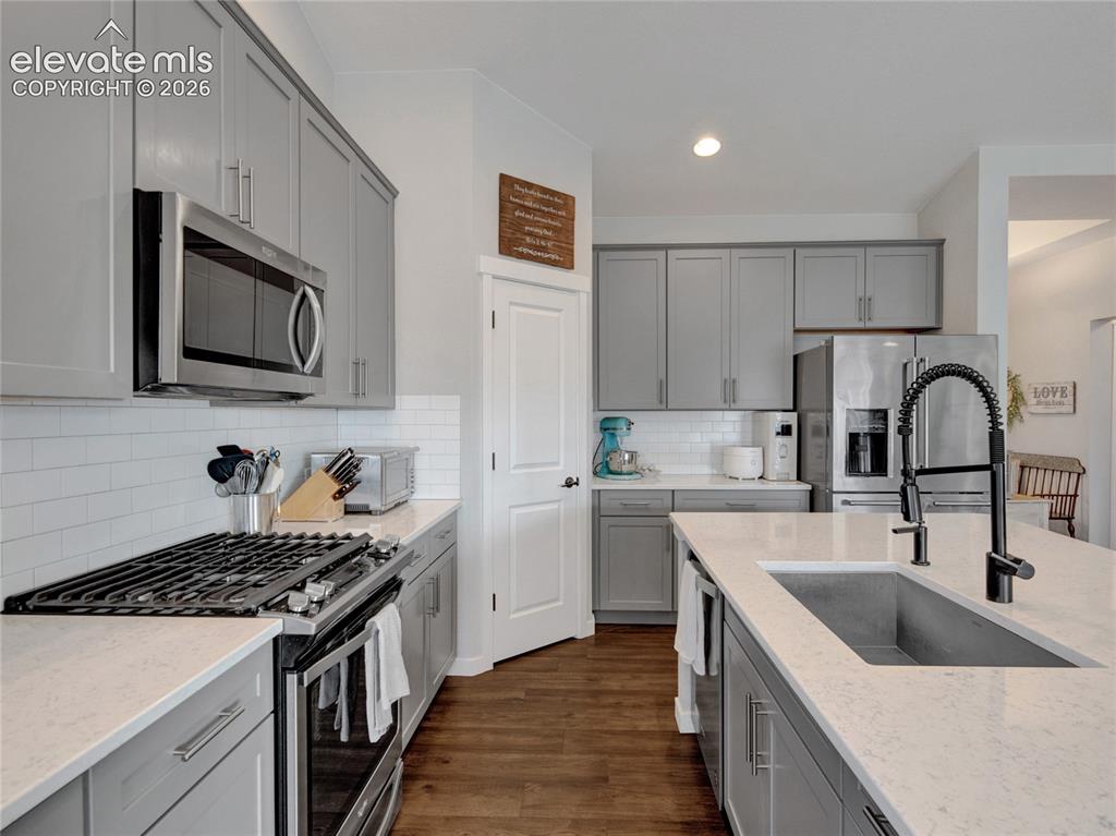 Image 6 of 17: Modern kitchen featuring gray cabinetry, white countertops, stainless steel