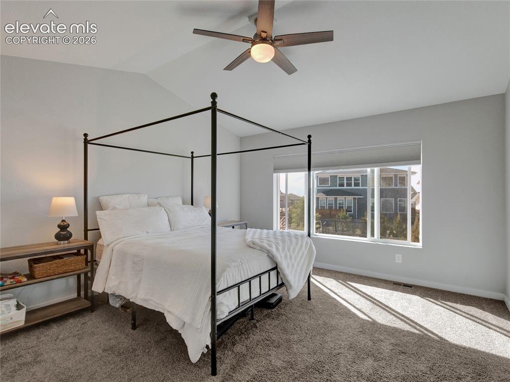 Image 7 of 17: Carpeted bedroom with vaulted ceilings, a ceiling fan with integrated light