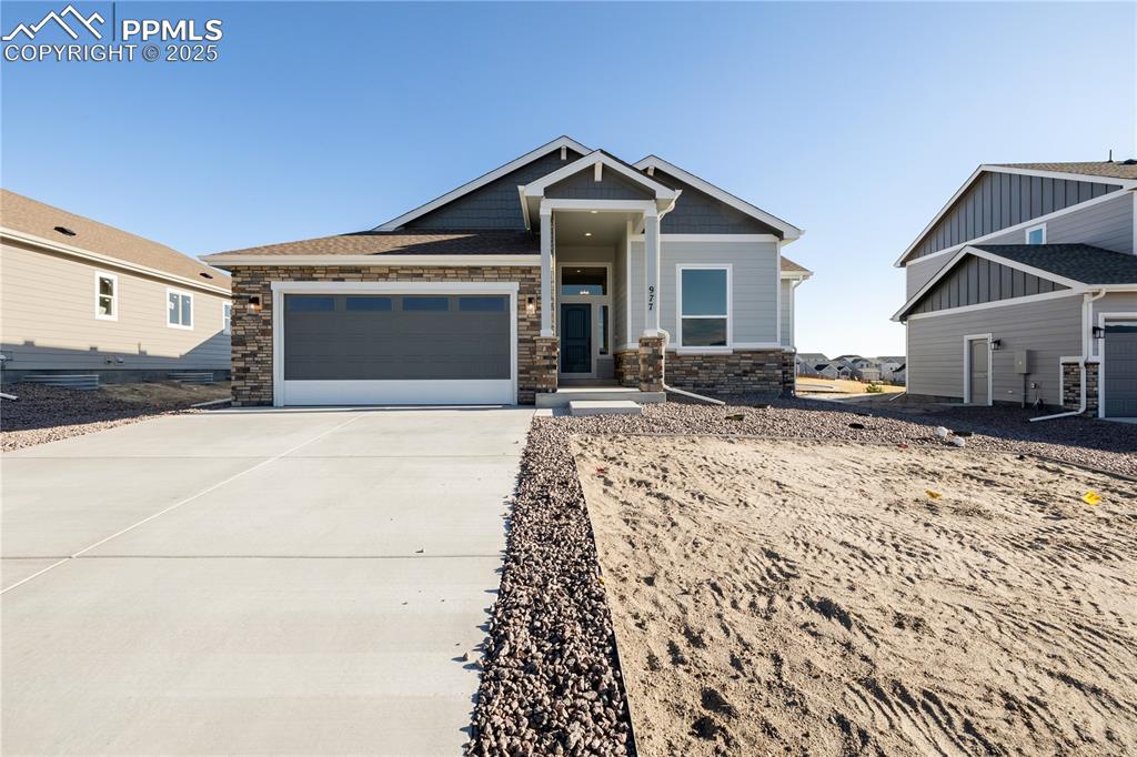 Image 1 of 40: Craftsman-style house with stone siding, driveway, and an attached garage
