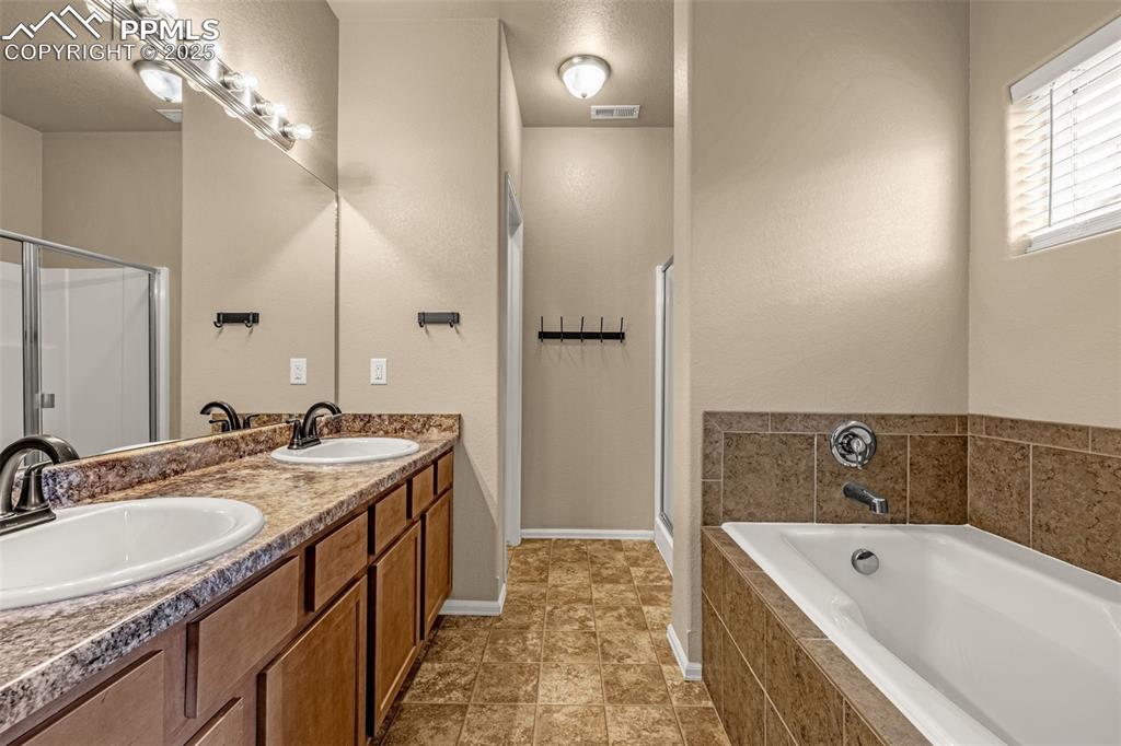 Image 16 of 28: Primary Bathroom with smooth counters, shaker style cabinets offering plent