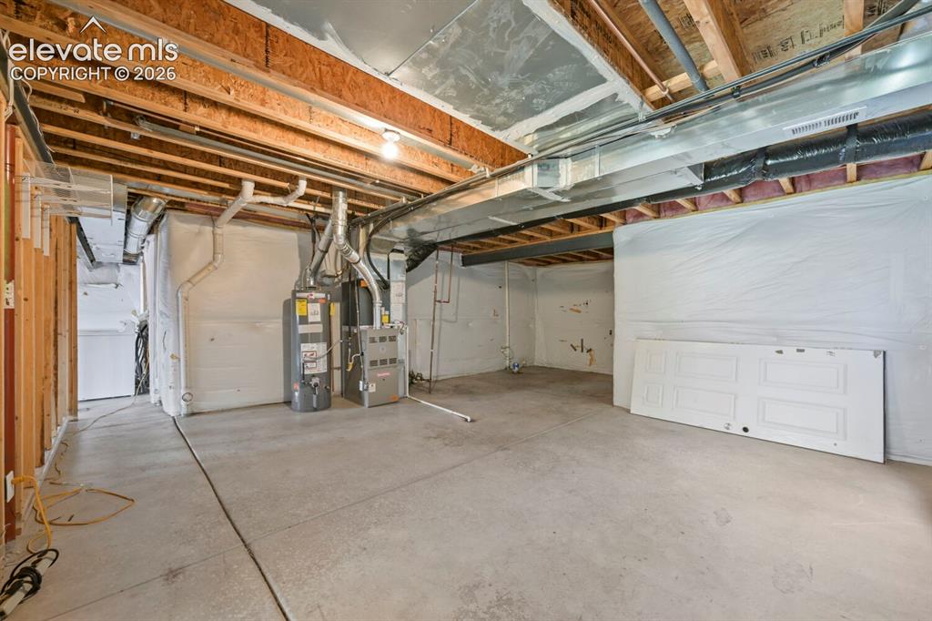 Image 16 of 45: Unfinished basement offering expansive concrete flooring and exposed ceilin