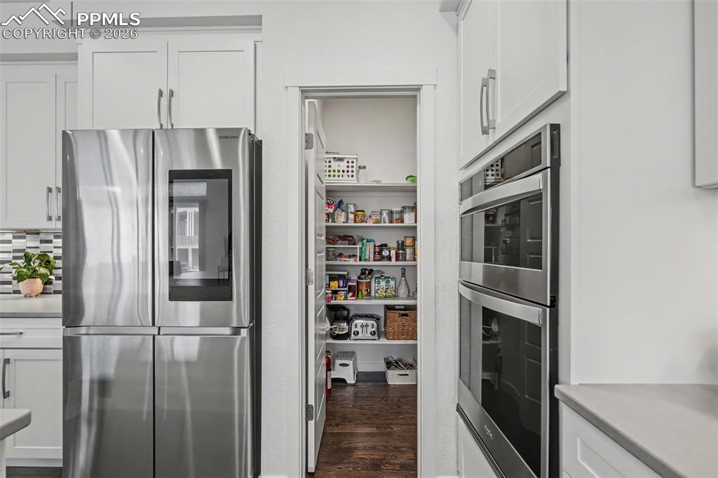 Image 10 of 37: Kitchen featuring white cabinets, stainless steel gas cooktop, suspended li