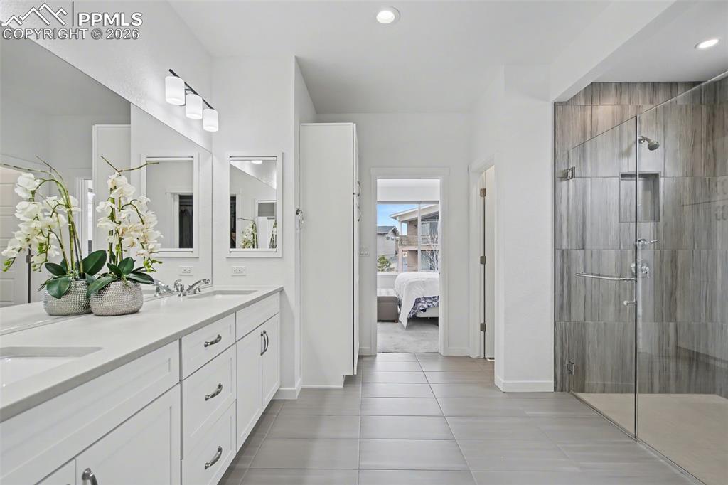 Image 13 of 37: Kitchen with white cabinetry, range hood, stainless steel appliances, decor
