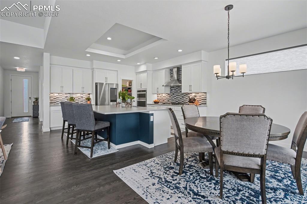 Image 7 of 37: Living room with dark wood finished floors, a stone fireplace, and recessed