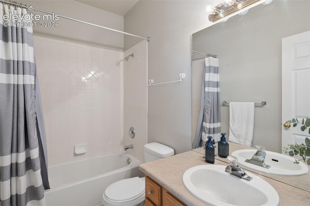 Image 10 of 37: Full bathroom featuring a tub-shower combination with tile surround, vanity